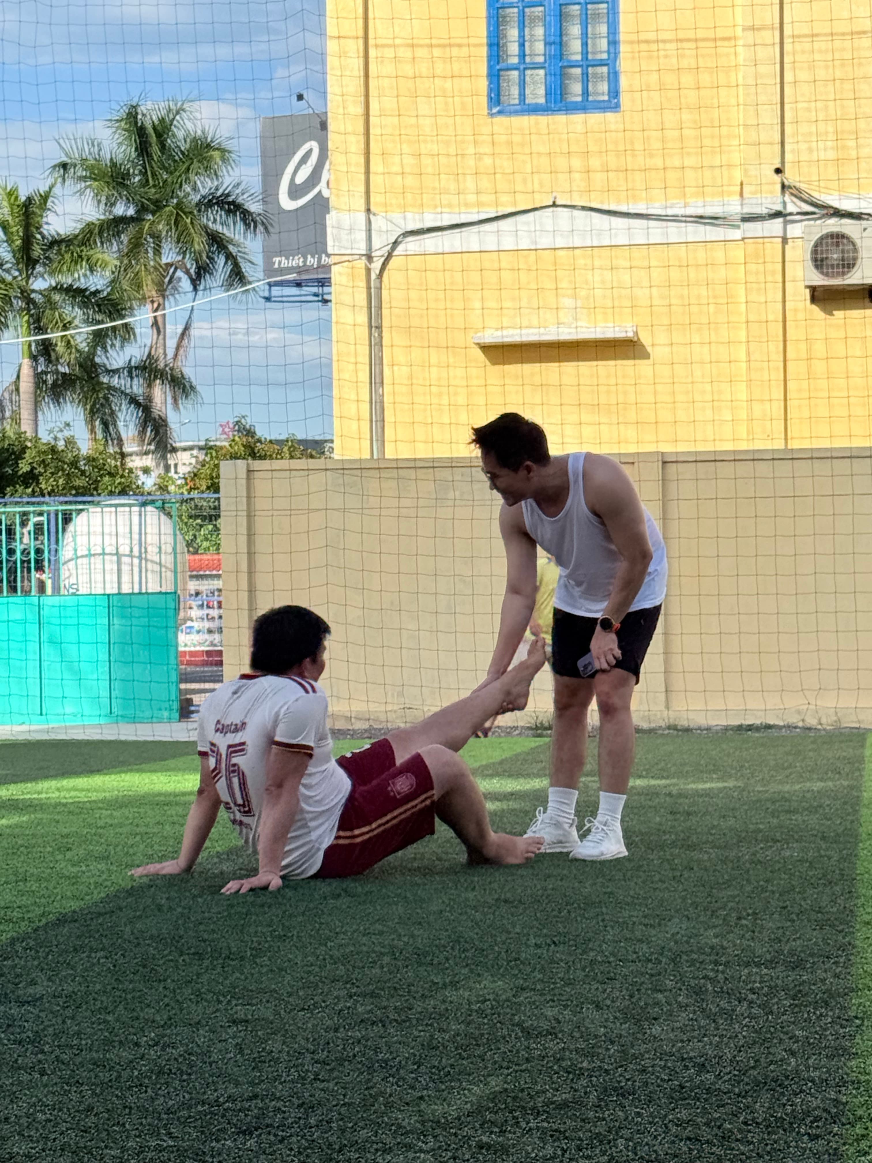 Một thành viên hỗ trợ cầu thủ đang ngồi trên sân